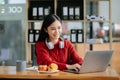 Attractive happy young Asian student studying at the college library, sitting at desk, using a laptop computer, tablet and Royalty Free Stock Photo