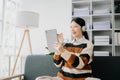 Attractive happy young Asian student studying at the college library, sitting at sofa, using a laptop computer, tablet and Royalty Free Stock Photo