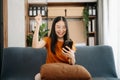 Attractive happy young Asian student studying at the college library, sitting at the sofa, using a laptop computer, tablet and Royalty Free Stock Photo