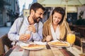 Happy young couple having good time in cafe restaurant. They are smiling and eating a pizza Royalty Free Stock Photo