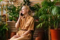 Attractive happy young woman floral shop owner sitting in own floral shop and talking on smartphone with client. Royalty Free Stock Photo