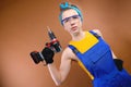 Attractive harsh young woman in overalls overalls and goggles with a screwdriver in her hand on a brown background