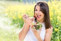 Attractive healthy girl eating green salad outdoors.