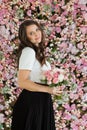 Attractive healthy woman smiling and holding colorful pink color flower bouquet on floral spring or summer background, studio Royalty Free Stock Photo