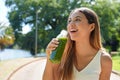 Attractive healthy young woman drinking green smoothie detox juice in city park Royalty Free Stock Photo