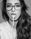 Attractive hipster girl in glasses holding cigarette at tongue. Beautiful sexy brunette with a cigarette stylish Royalty Free Stock Photo