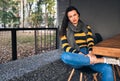 Attractive hipster girl sitting outdoors at comfortable cafeteria while waiting her lunch. Happy young woman sitting outdoors in Royalty Free Stock Photo