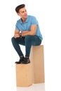 Attractive hipster seated on boxes