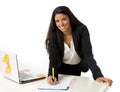 Attractive hispanic businesswoman or secretary taking notes standing leaning on office computer desk Royalty Free Stock Photo