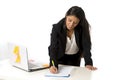 Attractive hispanic businesswoman or secretary taking notes standing leaning on office computer desk Royalty Free Stock Photo