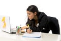 Attractive hispanic businesswoman or secretary taking notes standing leaning on office computer desk Royalty Free Stock Photo