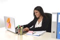 Attractive hispanic businesswoman sitting at office desk working on computer laptop smiling happy Royalty Free Stock Photo