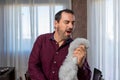 Attractive hispanic man with a beard in a purple shirt singing using a cleaning duster microphone Royalty Free Stock Photo