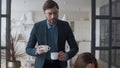 Attractive husband bringing tea cups to wife at home. Woman talking with man.