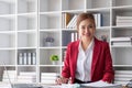 Attractive and inspired asian businesswoman sits at her desk, looking out the window, and daydreaming about her career Royalty Free Stock Photo