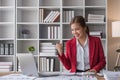 Attractive and inspired asian businesswoman sits at her desk, looking out the window, and daydreaming about her career Royalty Free Stock Photo