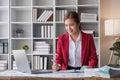 Attractive and inspired asian businesswoman sits at her desk, looking out the window, and daydreaming about her career Royalty Free Stock Photo