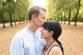 Attractive international couple in beautiful park kissing each other Royalty Free Stock Photo