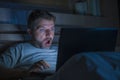Attractive internet addict man in shock and surprise networking late night on bed surprised face expression working with laptop Royalty Free Stock Photo