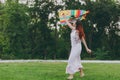 Attractive joyful smiling woman in light dress running, play with colorful kite and have fun in green park. Mother Royalty Free Stock Photo