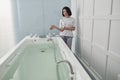 Attractive lady assistant invites to take hydro massage bath in spa salon Royalty Free Stock Photo