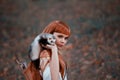 Attractive lady playfully and temptingly looks into camera, girl with fiery red hair and bangs holds cute tamed ferret