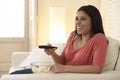 Attractive latin woman at home sofa couch laughing and smiling happy watching television Royalty Free Stock Photo