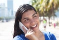 Attractive latin woman with long dark hair at phone in city Royalty Free Stock Photo