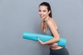 Attractive laughing sportswoman holding yoga mat