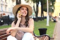 Attractive laughing woman talking on cellphone while sitting on bench outdoors