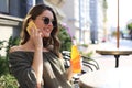 Attractive laughing woman talking on cellphone while sitting in cafe outdoors