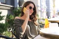 Attractive laughing woman talking on cellphone while sitting in cafe outdoors