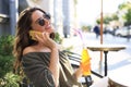 Attractive laughing woman talking on cellphone while sitting in cafe outdoors