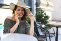 Attractive laughing woman talking on cellphone while sitting in cafe outdoors