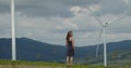 Attractive litle girl walking near a field with alternative green energy windmills Royalty Free Stock Photo