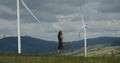 Attractive litle girl walking near a field with alternative green energy windmills Royalty Free Stock Photo