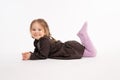 Attractive little child in dress liying on the floor and looking at the camera isolated over white background