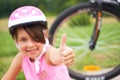 Attractive little cyclist giving thumbs up. Happy joyful little girl with bicycle on the background gesturing thumb up Royalty Free Stock Photo