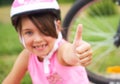 Attractive little cyclist giving thumbs up. Happy joyful little girl with bicycle on the background gesturing thumb up Royalty Free Stock Photo