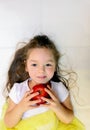 Attractive little girl is holding a red apple in her hand