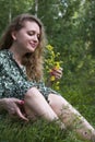 Attractive girl in the forest in a dress sits under a tree in the grass Royalty Free Stock Photo