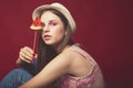 Attractive Lovely girl with pink make up, wearing jeans, hat and top, posing at red studio background, holding slice watermelon Royalty Free Stock Photo