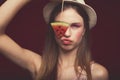 Attractive Lovely girl with pink make up, wearing jeans, hat and top, posing at red studio background, holding slice watermelon Royalty Free Stock Photo