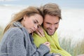 The attractive lovely woman and man sit in the sand dune of a beach relaxing - autumn, beach, sea Royalty Free Stock Photo