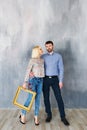 Attractive loving couple are standing near the texture wall, look at the camera and smiling.