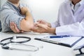 Attractive Male doctor Examining discussing reports with Massage patient suffering from back pain in clinic. Royalty Free Stock Photo