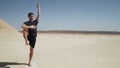 Attractive male doing yoga utthita hasta padangusthasana on a rock in desert