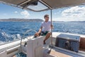 Attractive male skipper navigating the fancy catamaran sailboat on sunny summer day on calm blue sea water.