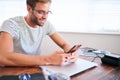 Attractive male student busy messaging on his cellphone at desk Royalty Free Stock Photo