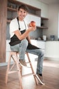 Attractive man with an apple sitting in a home kitchen Royalty Free Stock Photo